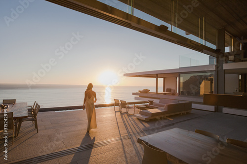 Woman walking on sunset modern, luxury home showcase exterior patio with ocean view photo