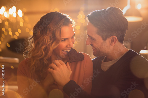 Affectionate couple biting heart-shape chocolate cookie