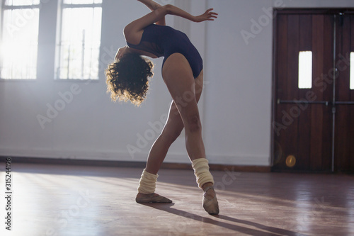 Graceful young female dancer dancing in dance studio photo