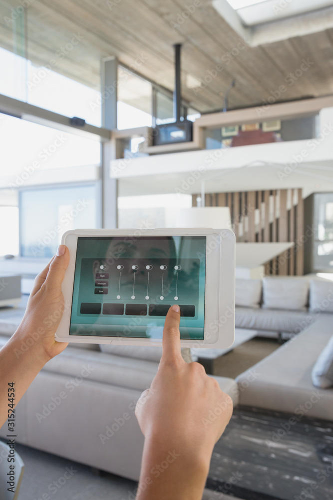 Personal perspective woman with digital tablet setting digital climate control in modern, luxury home showcase interior living room Personal perspective woman with digital tablet setting digital climate control in modern, luxury home showcase interior living room