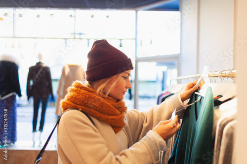 Young woman shopping in clothing store, checking price tag