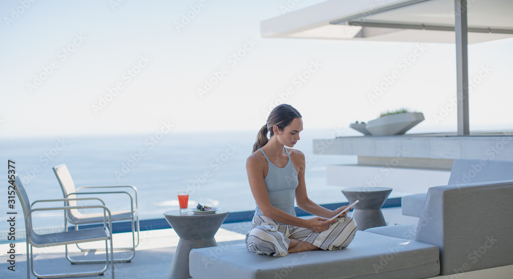 © Tom Merton/Caia Image - Woman in pajamas using digital tablet on modern, luxury home showcase exterior patio with ocean view © Tom Merton/Caia Image - Woman in pajamas using digital tablet on modern, luxury home showcase exterior patio with ocean view