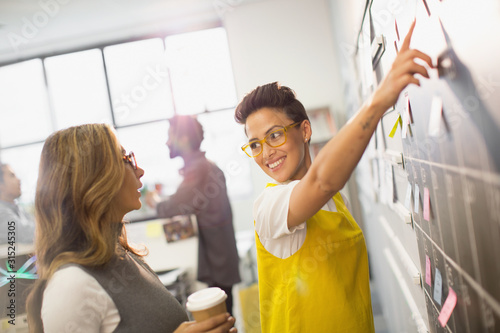 Creative businesswomen planning, scheduling at calendar blackboard