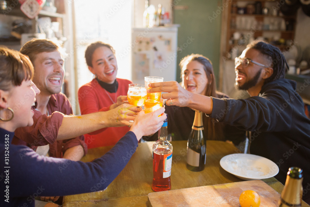 Young adult friends toasting cocktails at apartment kitchen table Young adult friends toasting cocktails at apartment kitchen table