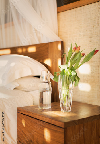 Tulip bouquet and water pitcher on bedside table in tranquil bedroom photo