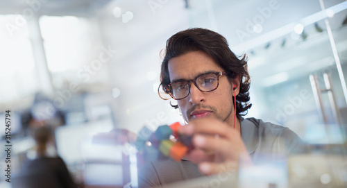 Focused, innovative male entrepreneur examining prototype in office