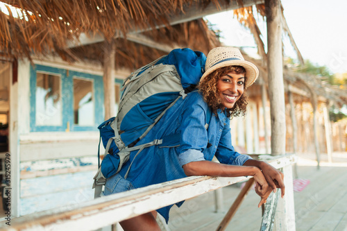 Portrait happy young female backpacker on beach hut patio photo