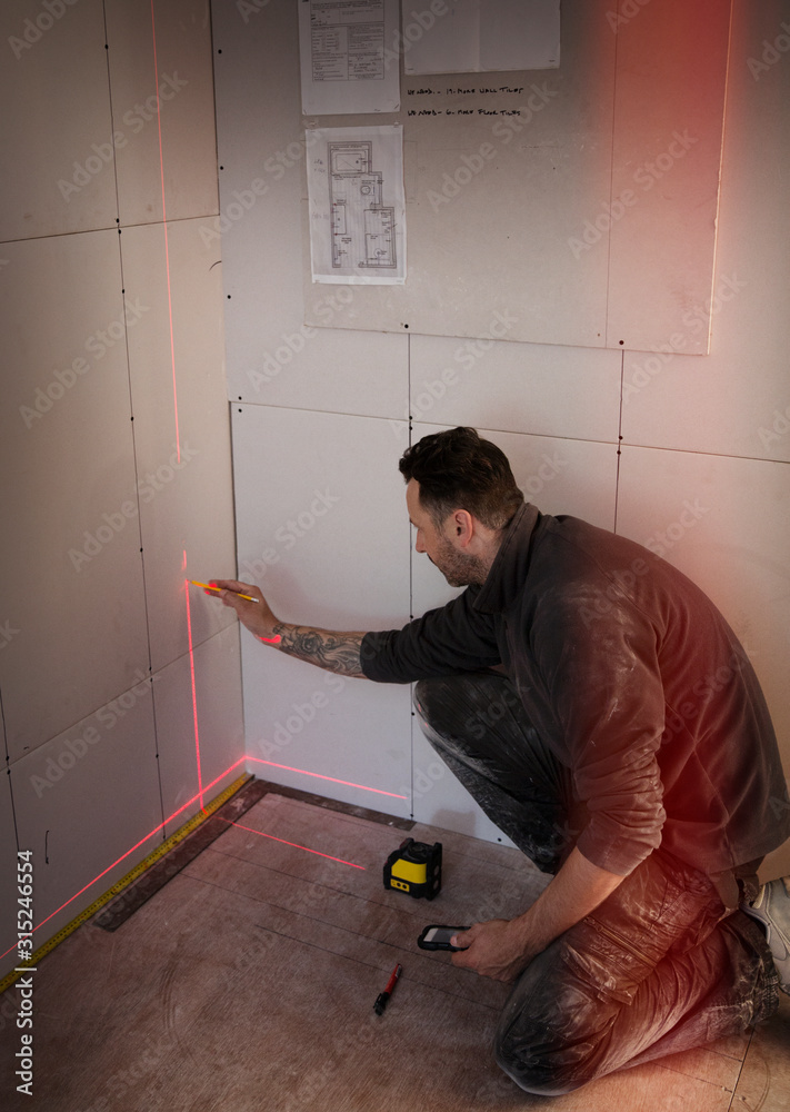 Construction worker using laser measuring tool Construction worker using laser measuring tool