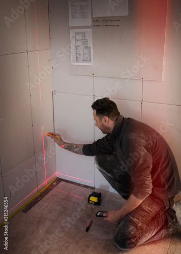 Construction worker using laser measuring tool photo