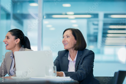 Smiling businesswomen listening in conference room meeting photo