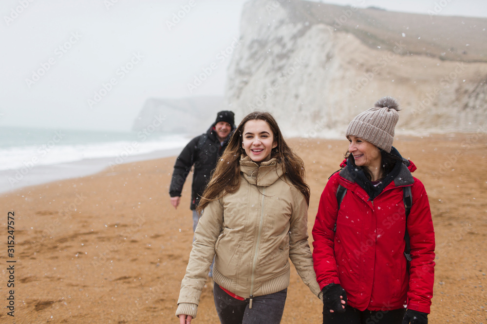 Affectionate mother and daughter walking on snowy winter beach Affectionate mother and daughter walking on snowy winter beach