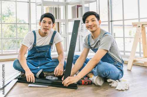 profession, carpentry, woodwork and people concept - two carpenters with electric drill drilling wood plank at workshop.