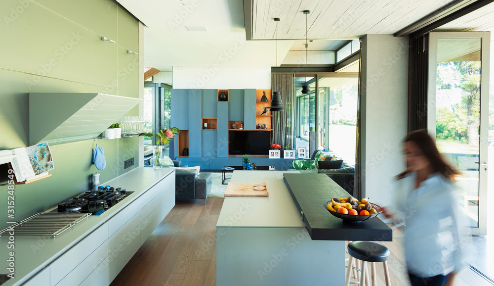 Woman walking in modern, luxury kitchen Woman walking in modern, luxury kitchen