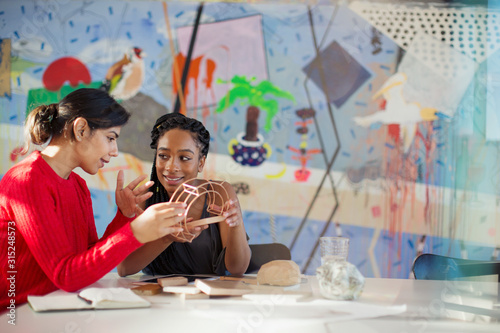 Female engineers examining prototype in creative conference room photo