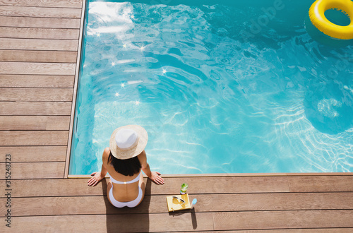 Woman in sun hat relaxing at sunny summer poolside