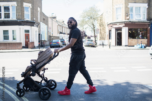 Portrait happy father pushing toddler son in stroller on sunny urban street photo