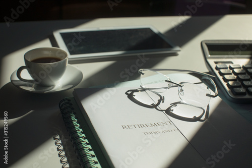 Retirement portfolio on sunny desk with coffee and eyeglasses photo