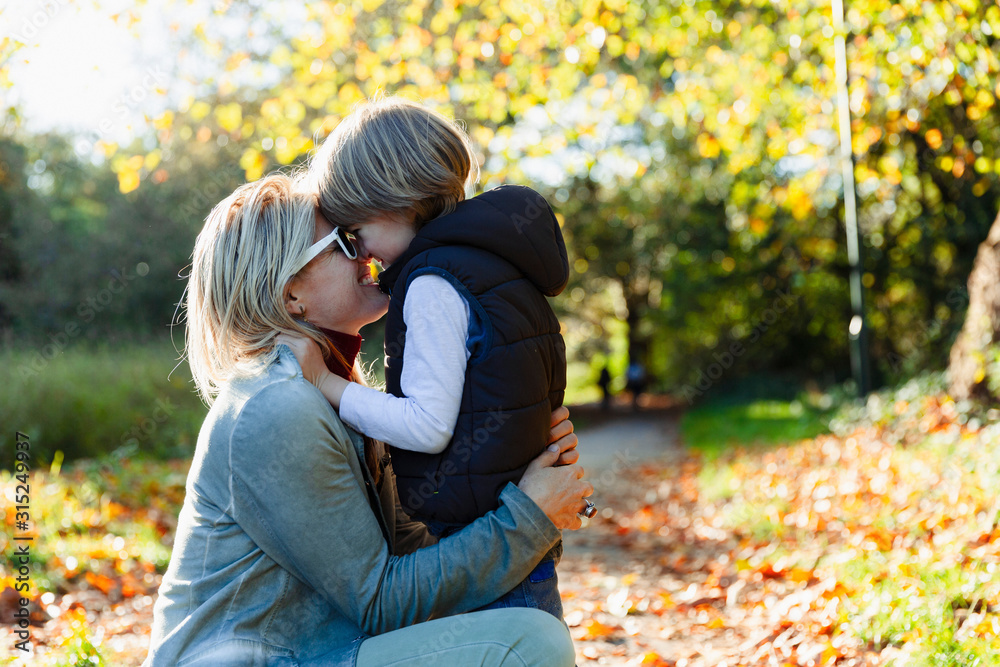 Affectionate mother and son hugging in sunny autumn park