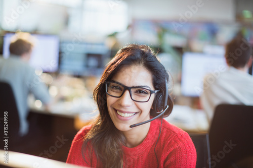 Portrait confident, smiling businesswoman with headset working in office