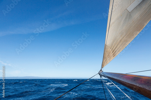Wooden sailboat mast over sunny blue Atlantic Ocean photo