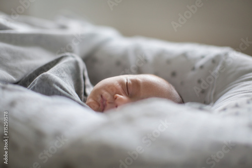 Tired innocent newborn baby boy sleeping in Moses sleeper basket photo
