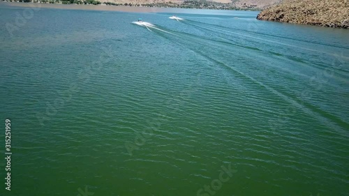 Dramatic Tilt Up Aerial View on Two Speedboats Sailing on Green Water of Topaz Lake USA, Reservoir in Desert of Nevada California Border photo