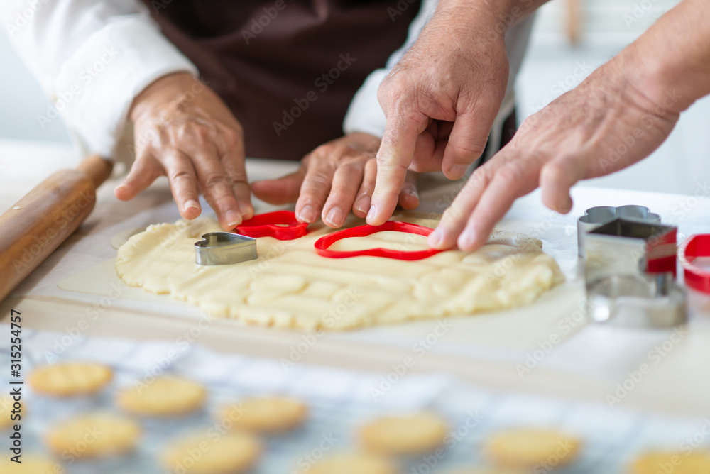 Close up Senior Couple Hands making cookies with red cutters in heart shape. Close up Senior Couple Hands making cookies with red cutters in heart shape.