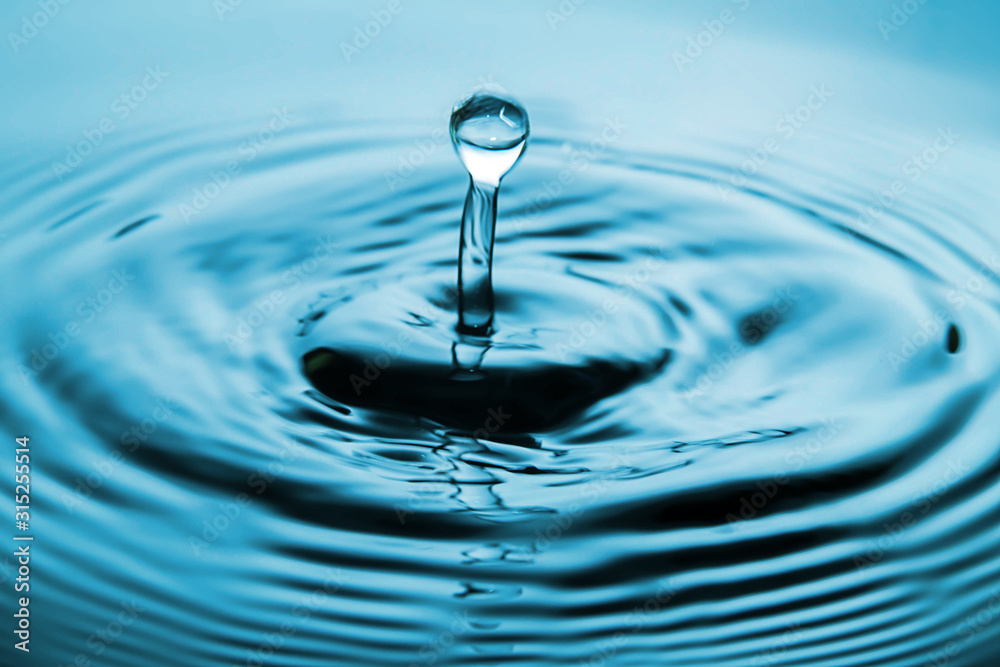 Closeup Water drop falling on the surface of the water and beautiful circular wave ripple, fresh natural mineral water drink water concept Closeup Water drop falling on the surface of the water and beautiful circular wave ripple, fresh natural mineral water drink water concept