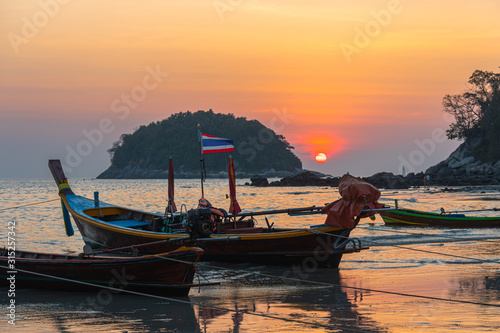 round red sun in sunset above fishing boats in Kata beach Phuket Thailand © Narong Niemhom