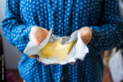 Woman hands holds fresh homemade butter packed into packaging foil.