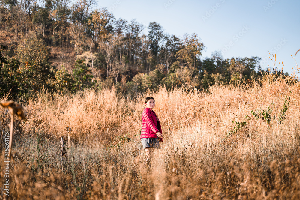 A girl walking on a mountain of brown grass