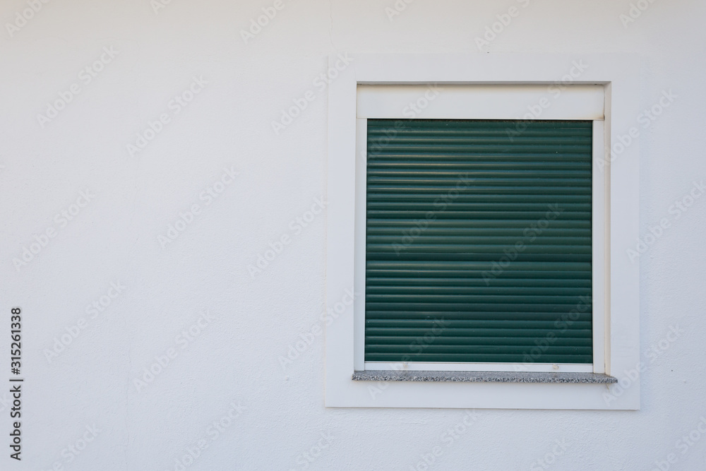 White plastic window with green shutters.