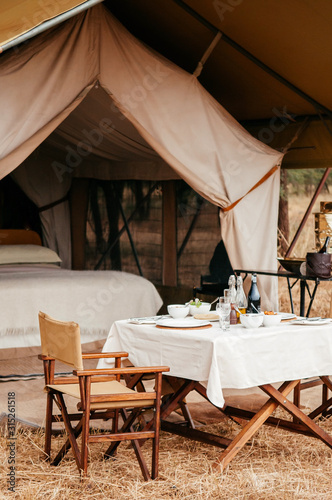 Luxury Safari tent camp with picnic table in Serengeti Savanna forest - Glamping travel in Africa wild forest