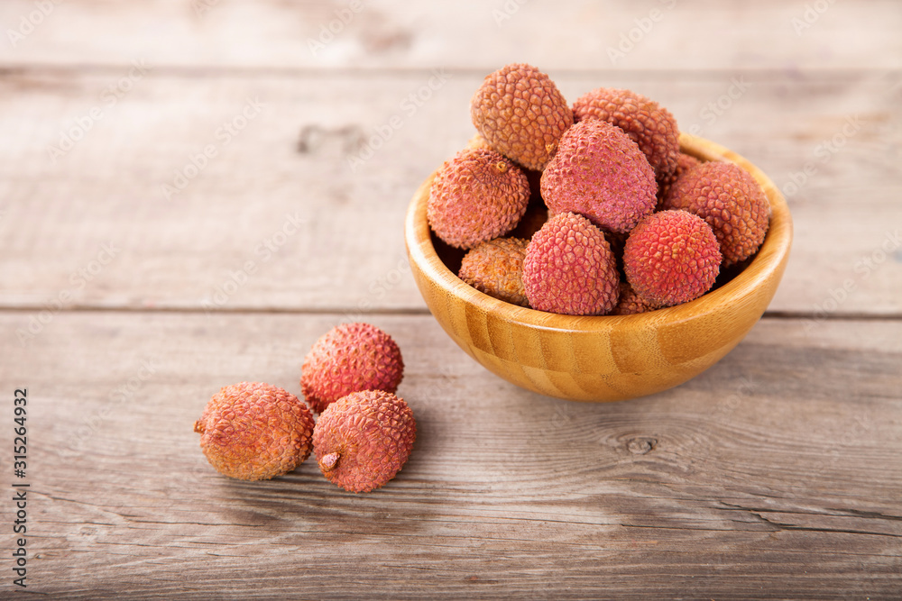 Fruits lychee in a bowl on a wooden background. Selective focus. Copy space. Fruits lychee in a bowl on a wooden background. Selective focus. Copy space.