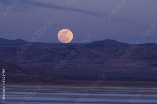 Canvas Print Full moon rising over mountains in the Mojave Desert, California, United States