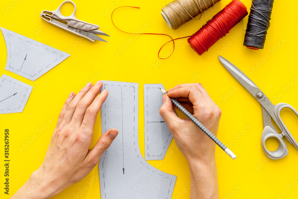 Tailor working. Women hands drawing patterns for clothes on yellow  background top-down Stock Photo | Adobe Stock