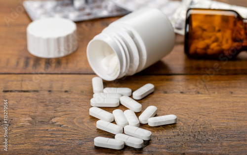 A medical set-up. Plastic white and glass bottles. Medicinal blue and white pills.