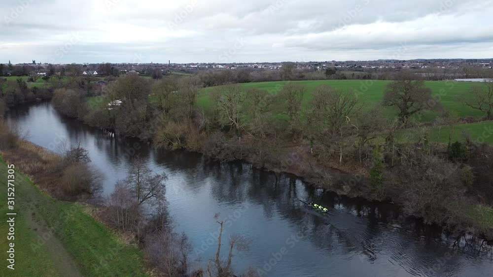 A grey yet picturesque English countryside shot with some passing rowers A grey yet picturesque English countryside shot with some passing rowers