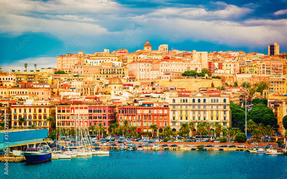 Old Sardinian Port with ships at Mediterranean Sea and city of Cagliari, South Sardinia Island in Italy in summer. Cityscape with marina and Yachts and boats in town