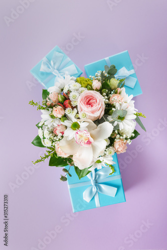 Composition of bouquet of flowers and gift boxes on a colorful background flat lay top view
