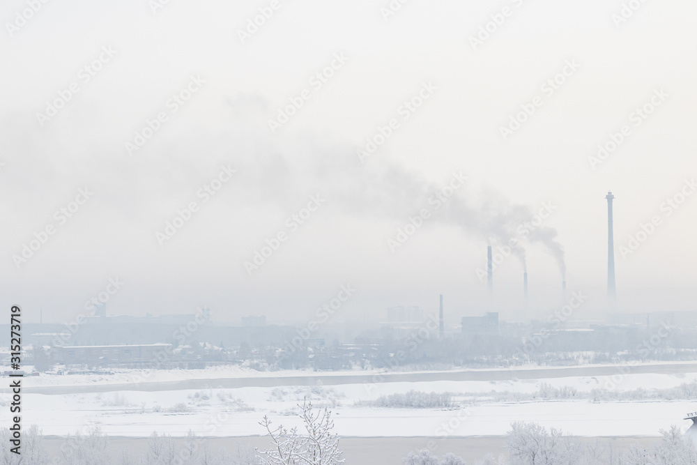 Winter cityscape - high pipes of a power plant and smoke against