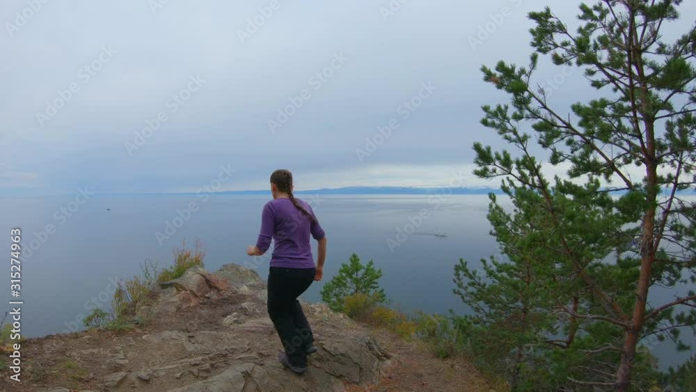 Girl runs up the cliff, jumps up and raises her hands. Slow motion Girl runs up the cliff, jumps up and raises her hands. Slow motion