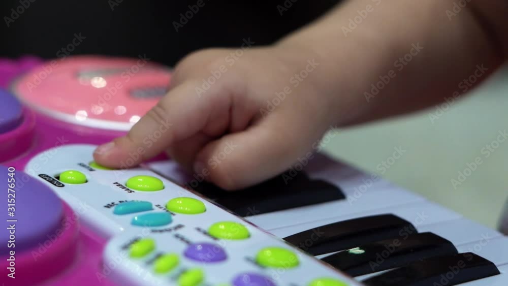 The baby learns to play the children's electronic piano. He is in his room. There's a children's tent behind him. The baby learns to play the children's electronic piano. He is in his room. There's a children's tent behind him.