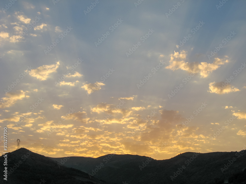Dramatic sunset cloudy sky with clouds lit by sunset sunlight. Sunset sky background -orange and blue dramatic colorful clouds lit by evening sunset light. Natural sunset sky landscape view. Dramatic sunset cloudy sky with clouds lit by sunset sunlight. Sunset sky background -orange and blue dramatic colorful clouds lit by evening sunset light. Natural sunset sky landscape view.