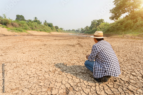 Farmer stand in the dry river and looking to empty water in Sukhothai. For drought season concept. photo