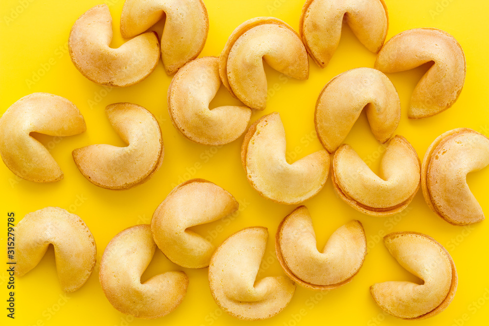 Fortune cookie background on yellow table top-down