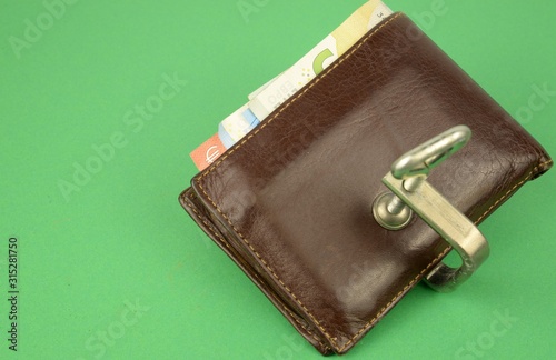 E' meglio investire che tenere i soldi fermi sul proprio conto: vecchio portafoglio contenente soldi tenuto chiuso da una morsa di metallo  photo
