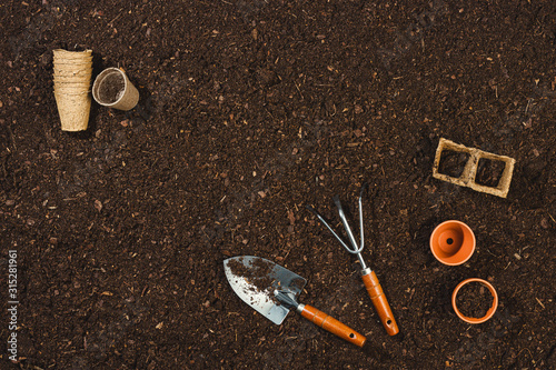 Gardening tools on soil texture background top view.