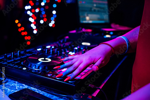 hand of a DJ girl on the background of a music controller mixer