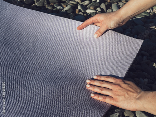 Yoga or Pilates Mat in women's hands. Training on the beach photo